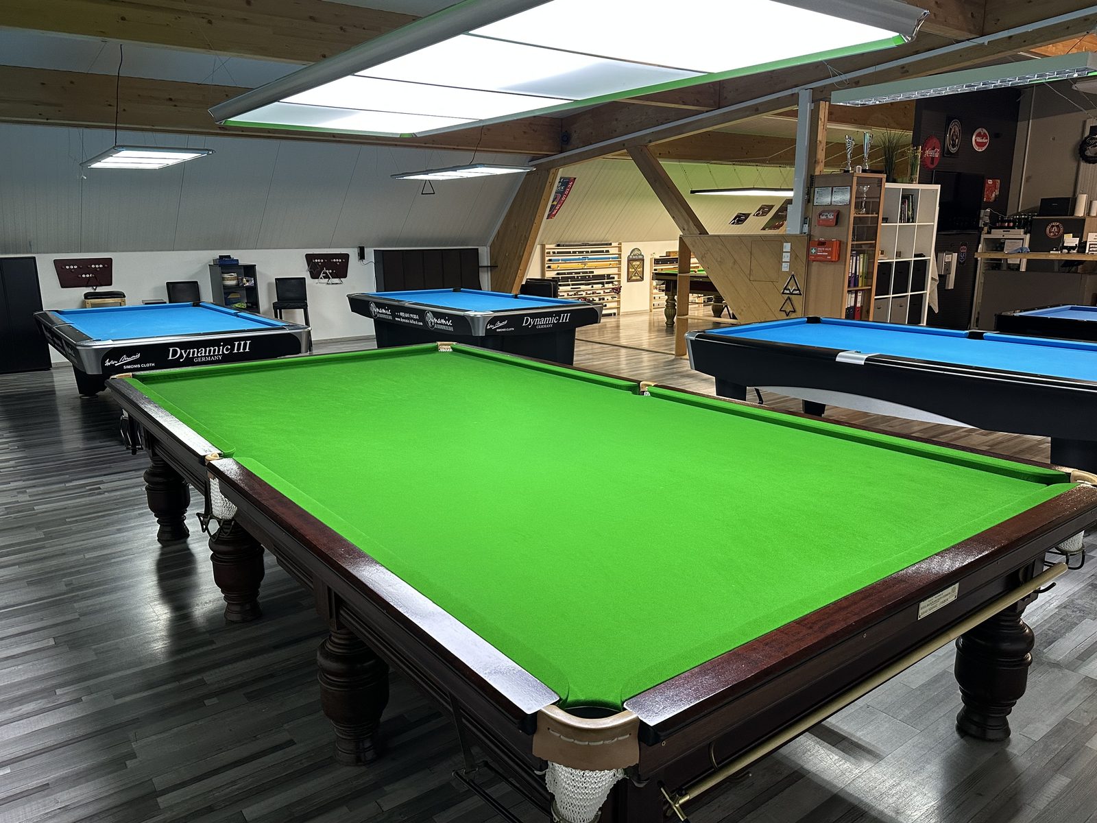 Ein Snookertisch im Vordergrund, dahinter Pooltische