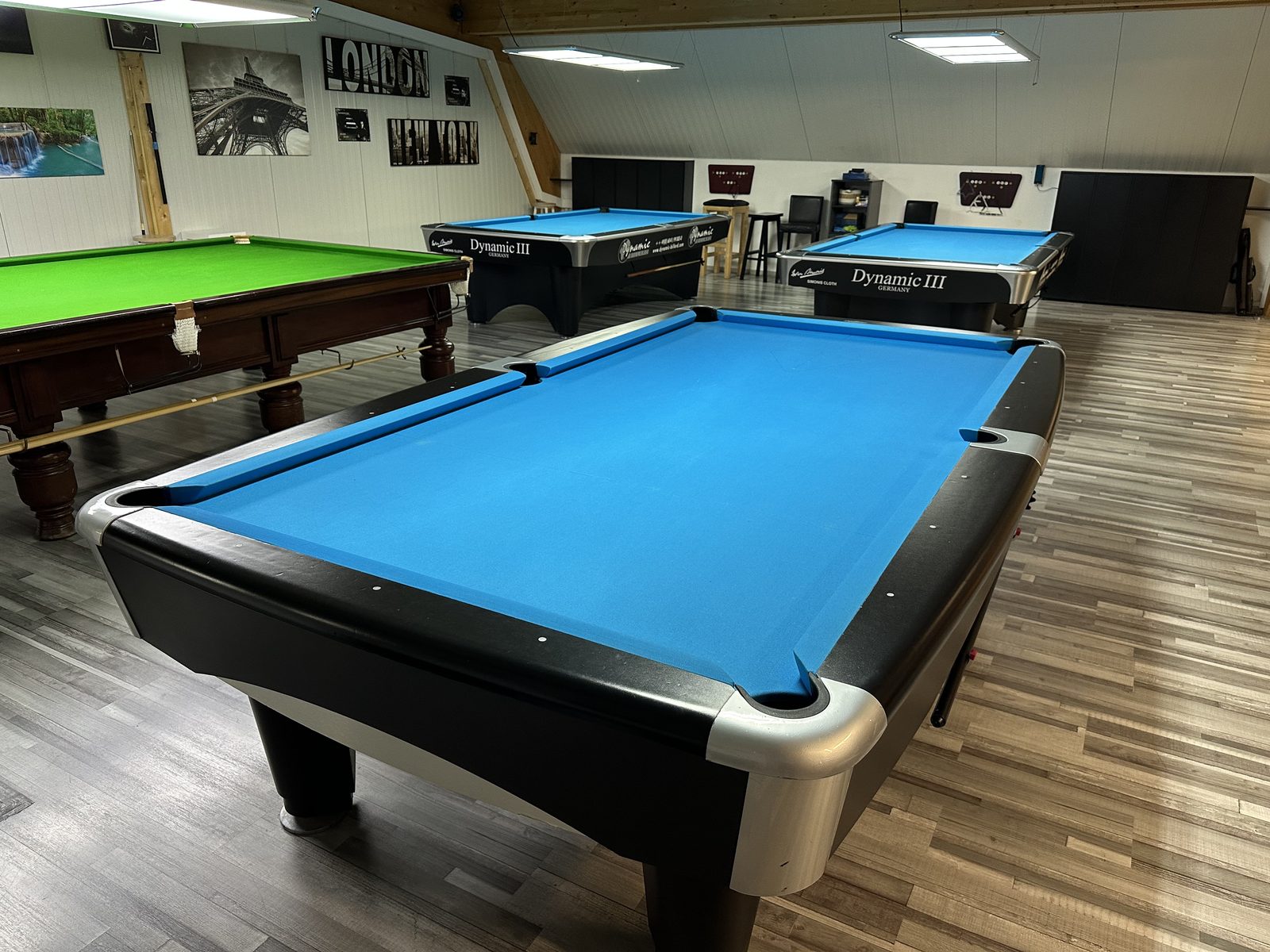 Ein Pooltisch mit blauem Tuch neben einem Snookertisch